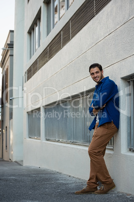 Smiling man with arms crossed leaning on wall