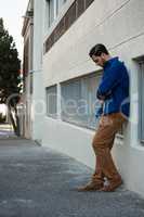 Man looking down while leaning on wall