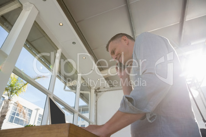 Designer talking on smart phone while standing at desk in office