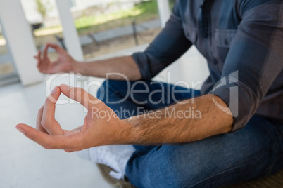 Businessman meditating while sitting on floor at office