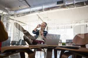 Businesswoman talking on smart phone while relaxing in office