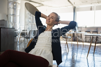 Thoughtful businesswoman with hands behind head relaxing on chair