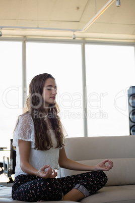 Young woman doing yoga in office