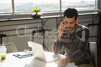 Businessman talking on phone at desk in office