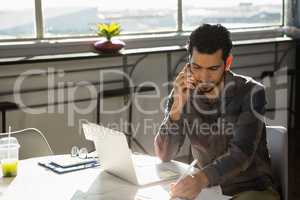 Businessman talking on phone at desk in office