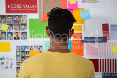 Rear view of man standing against sticky notes in office