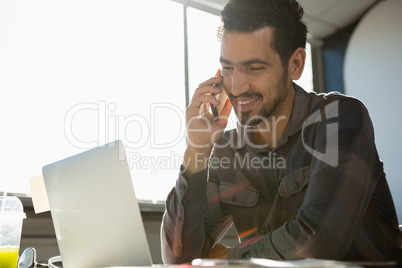 Smiling man talking on phone at office