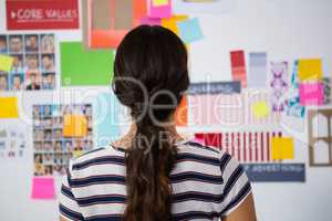 Rear view of businesswoman against sticky notes in office