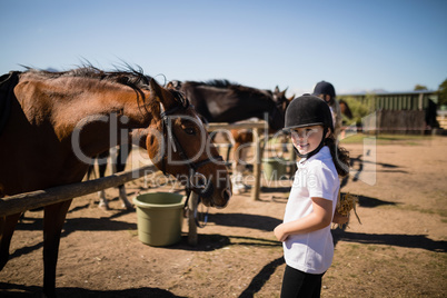 Smiling girl standing near the horse in ranch