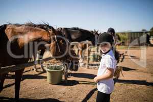 Smiling girl standing near the horse in ranch