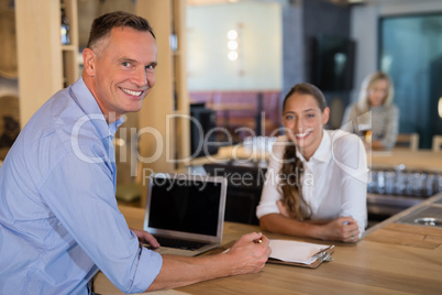 Smiling manager and bartender standing at bar counter