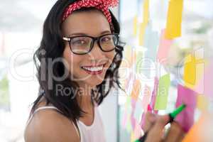 Female executive writing on sticky notes in office