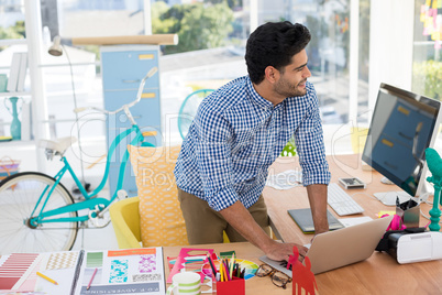 Graphic designer working on laptop at desk