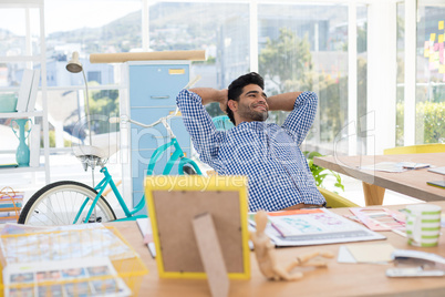 Male executive relaxing with hands behind head at desk