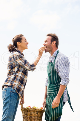 Smiling woman feeding apple to man