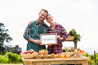 Portrait of couple with blank blackboard selling vegetables