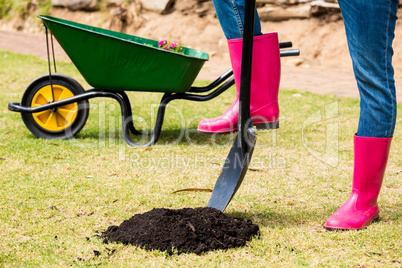 Low section of woman in pink boots with shovel