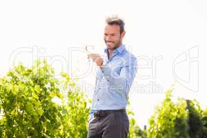 Smiling man holding wineglass against sky