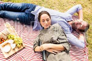 High angle view of couple sleeping on picnic blanket