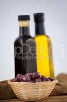 Close up of olives in wicker basket by oil bottles