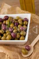Close up of olives with rosemary served in bowl on paper