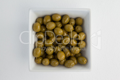 Overhead view of green olives in white container