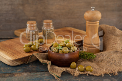 Olives in bowl by pepper shaker on burlap