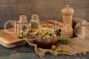 Olives in bowl by pepper shaker on burlap