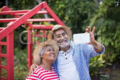 Senior couple taking selfie while standing in yard