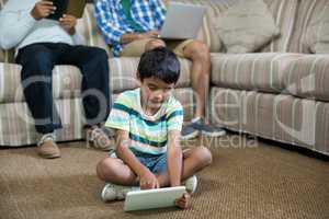 Boy using tablet with father and grandfather in background