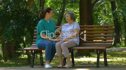 Young nurse spending sunny day with senior woman in park