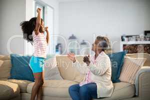 Grandmother applauding her granddaughter while dancing in living room