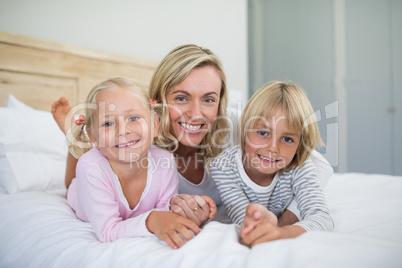 Mother with daughter and son relaxing on bed in the bedroom