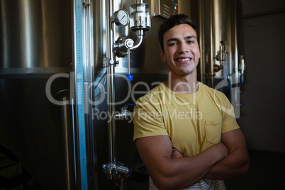 Portrait of male worker with arms crossed by storage tanks