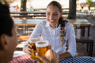 Happy woman with friend toasting beer