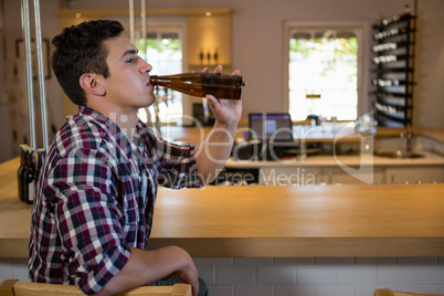 Young man drinking beer at counter