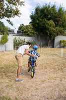 Rear view of father assisting son while riding bicycle