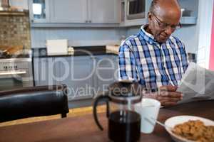 Man reading newspaper while having breakfast