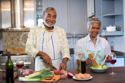Portrait of senior couple preparing food at home