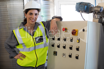 Portrait of female technician standing near machine