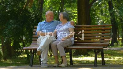 Senior couple relaxed talking on the park bench