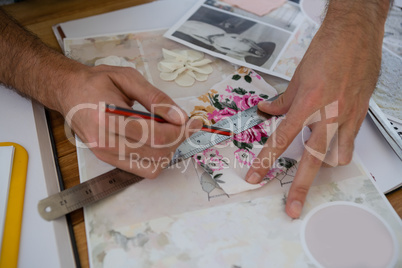 Cropped hands of designer drawing line on paper at table
