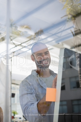 Smiling designer using computer in studio seen through glass