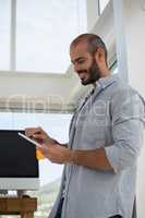 Low angle view of designer using digital tablet while leaning on wall