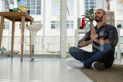 Businessman in prayer position meditating at studio