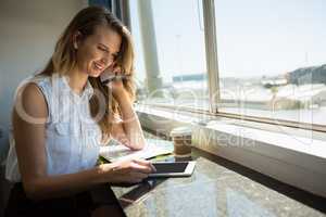 Businesswoman talking on mobile phone while using digital tablet