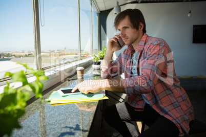 Businessman talking on phone while using digital tablet