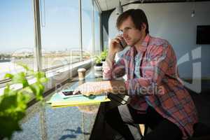 Businessman talking on phone while using digital tablet