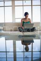 Woman using laptop while sitting on sofa at office