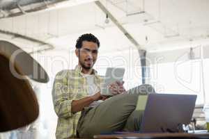 Portrait of young man using tablet in office